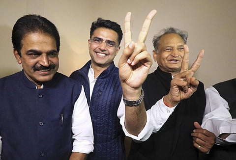 Congress leaders Ashok Gehlot (R) and Sachin Pilot (C) flash victory signs as K.C. Venugopal looks on after the declaration of Rajasthan Assembly election result in Jaipur. (PTI File)
