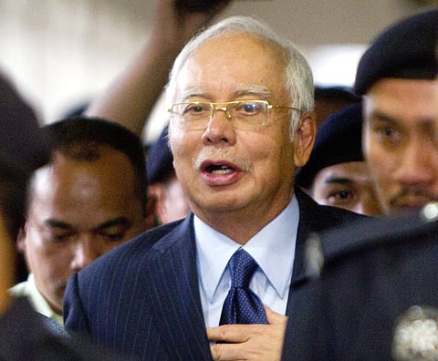 file photo, former Malaysian Prime Minister Najib Razak walks out of courtroom after a court hearing at Kuala Lumpur High Court in Kuala Lumpur, Malaysia. Malaysia says it has filed criminal charges against Goldman Sachs and two of its employees in connec