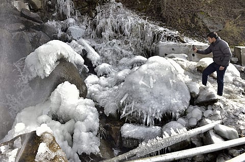 A tourist takes photos of icicles formed due to burst of a water supply line during a snowfall at Pahalgam in Anantnag district of south Kashmir Sunday December 23 2018. | PTI