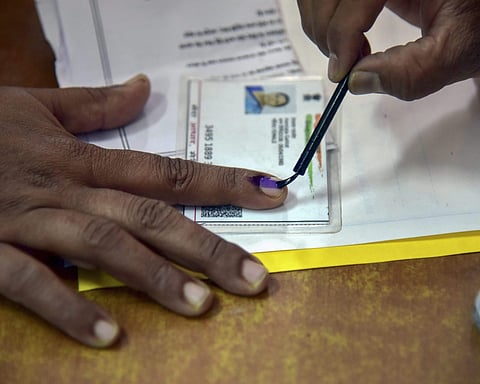 An election officer put an indelible ink mark on the finger of a voter during the state Assembly elections in Bikaner. (Photo | PTI)