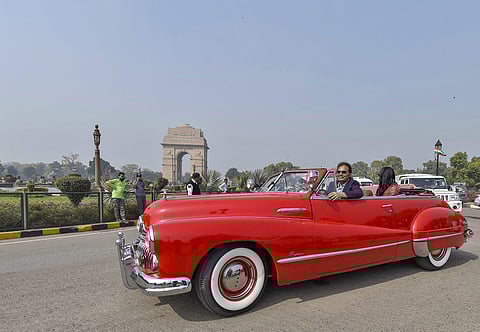 A family drives a vintage car around India Gate during the 8th edition of 21 Gun Salute International Vintage Car Rally in New Delhi. | PTI