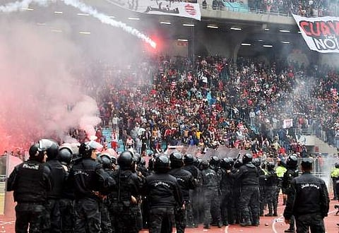 Tunisian policemen stand guard as fans throw flares during the Tunisia Ligue 1 football match derby | AP