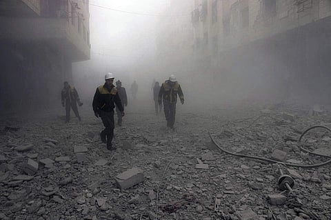 File: This photo provided by the Syrian Civil Defense group known as the White Helmets, shows civil defense workers searching for survivors after airstrikes hit a rebel-held suburb near Damascus, Syria, Monday, Feb. 5, 2018. The Syrian Observatory for Hum