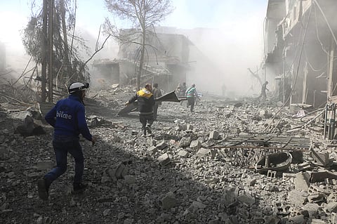 Members of the Syrian Civil Defense run to help survivors from a street that attacked by airstrikes and shelling of the Syrian government forces. | AP