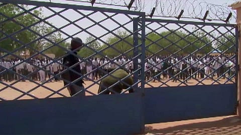 Armed police officers open school gates in response to government's latest moves to improve school security, as students wait to leave school, in Damaturu, Nigeria, Monday Feb.26, 2018. | AP
