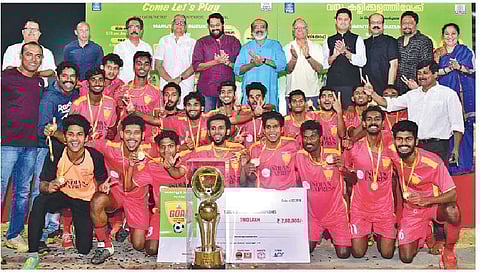 Members of the triumphant Sree Kerala Varma College, Thrissur team celebrate with the TNIE GOAL 2018 trophy as Finance Minister T M Thomas Isaac (sixth left) applauds. Also seen are (from left) Kerala Blasters FC Technical Director and assistant coach Tha