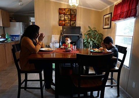 (L-R) Minerva Cisneros Garcia prays with her sons, Mateo and Antonio, before eating at their home in Winston-Salem, North Carolina, on February 12, 2018. Cisneros lived in sanctuary at the Congregational United Church of Christ before a federal judge in t