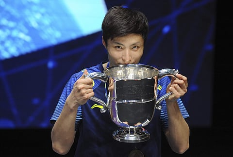China's Shi Yuqi poses with his trophy after defeating China's Lin Dan in the men's singles final match at the All England Open Badminton tournament in Birmingham. | Photo: AP