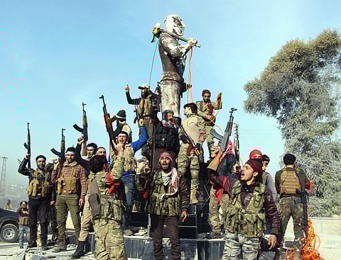 Turkey-backed Free Syrian Army soldiers celebrate around a statue of Kawa as they prepare to destroy it in city center of Afrin. | AP
