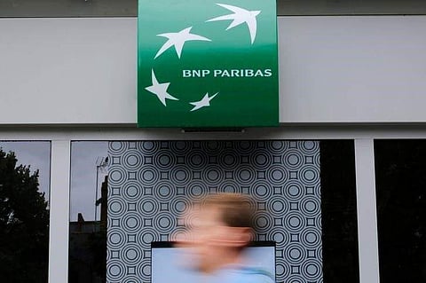 A man walks past a BNP Paribas bank sign on an office building in Nantes, France | Reuters