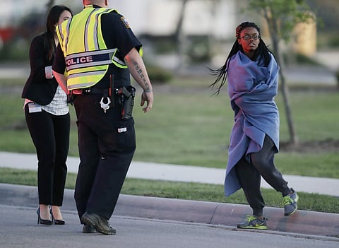 An employee wrapped in a blanket talks to a police officer after she was evacuated at a FedEx distribution center where a package exploded, Tuesday, | Photo: AP