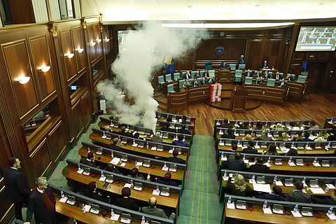 Opposition lawmakers release a tear gas canister disrupting a parliamentary session in Kosovo capital Pristina on Wednesday, March 21, 2018. Kosovo's Parliament, has temporarily suspended its session after tear gas disrupted the vote on a border demarcati