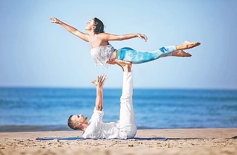 Goa-based certified AcroYoga teacher Yamuna Devi in front bird pose with trainer Marco acting as the base