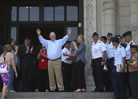 In this photo provided by Peru's presidential press office, Peru's President Pedro Pablo Kuczynski waves to government workers and supporters outside the House of Pizarro government palace and presidential residence one day after offering his resignation