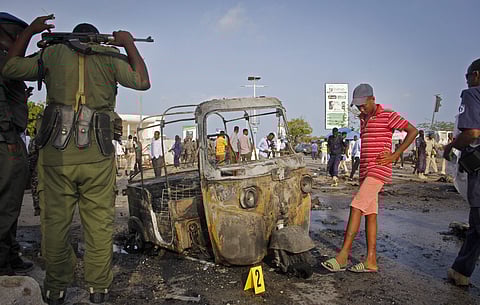 Somali soldiers and a boy stand near the wreckage of a three-wheeled motorcycle taxi at the scene of a car bomb explosion near the parliament building in the capital Mogadishu, Somalia (AP)