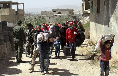 This photo released by the Syrian official news agency SANA, shows civilians carrying their belongings leaving towns and villages, in the eastern Ghouta region near Damascus, Syria. (AP)