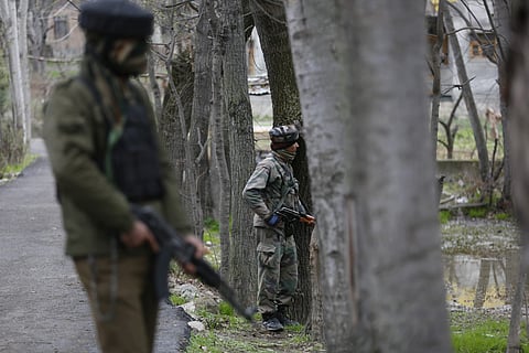 Indian army soldier takes position behind trees near a residential building in Srinagar. | AP