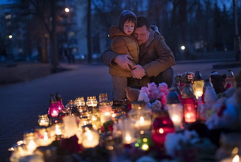 People light candles to commemorate the victims of Sunday's fire in a shopping mall in the Siberian city of Kemerovo, in front of the Russia's Embassy in Vilnius, Lithuania. | AP