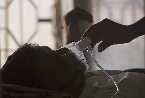 A relative adjusts the oxygen mask of a tuberculosis patient at a TB hospital in Hyderabad. | AP