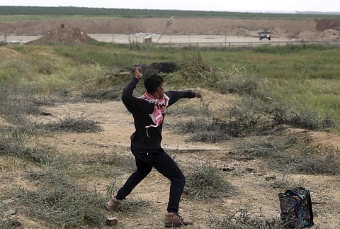 A Palestinian protester hurls stones toward Israeli soldiers during a demonstration near the Gaza Strip border with Israel, in eastern Gaza City. | AP