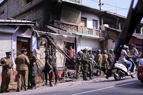 Sri Lanka's army soldiers and police personnel stand near a vandalized building in Digana, a suburb of Kandy. | AP