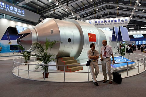 FILE - In this Nov. 16, 2010 file photo, visitors sit beside a model of China's Tiangong-1 space station at the 8th China International Aviation and Aerospace Exhibition in Zhuhai in southern China's Guangdong Province. | AP