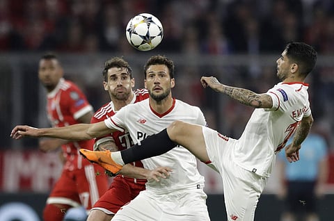 Sevilla's Ever Banega goes for the ball as Bayern's Javi Martinez, left, and Sevilla's Franco Vazquez look on during the Champions League quarter final second leg soccer match between FC Bayern Munich and Sevilla FC at the Allianz Arena stadium in Munich.