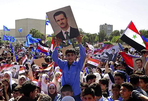 In this photo released by the Syrian official news agency SANA, protesters wave flags and portraits of President Bashar Assad, as they march during a demonstration to show solidarity with the Syrian armed forces, at Omayyad Square, in Damascus, Syria. | A