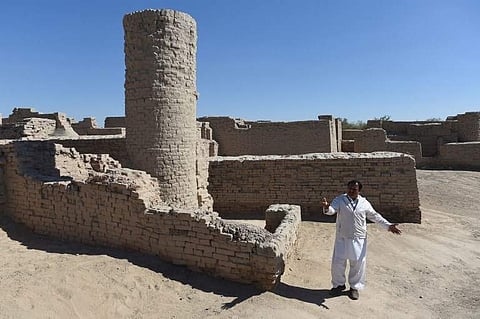 In this photograph taken on February 9, 2017, Pakistani caretaker at the UNESCO World Heritage archeological site of Mohenjo Daro, Ismail Mugheri, points out a two-story well used to collect drinking water at the site some 425 kms north of Karachi. | AFP