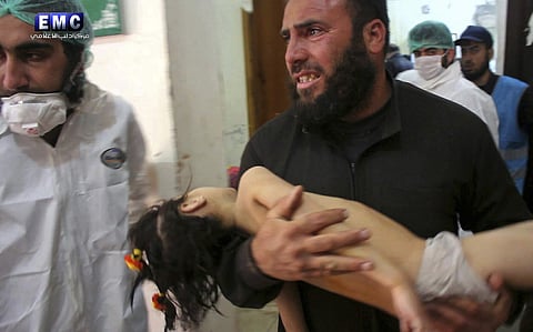 A man carrying a child following a suspected chemical attack. (Representational image | AP)