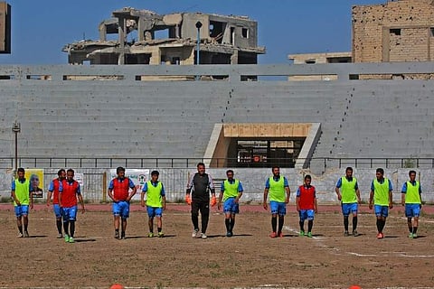 Syrians take part in a football match between local teams al-Sadd and Rashid at a stadium in Raqa, the former Islamic State group's Syrian capital, on April 16, 2018. | AFP