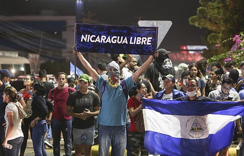 An anti-government protester holds up the Spanish sign: 'Nicaragua free' at the Jean Paul Jennie round-about where protesters pulled down a statue that is emblematic of the government of Nicaraguan President Daniel Ortega, in Managua, Nicaragua, Saturday,