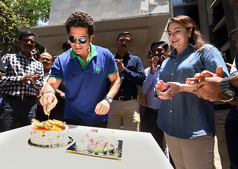 Cricket legend Sachin Tendulkar cuts a cake to celebrate his birthday with fans at his residence in Mumbai on Tuesday. His wife Anjali is also seen. | PTI