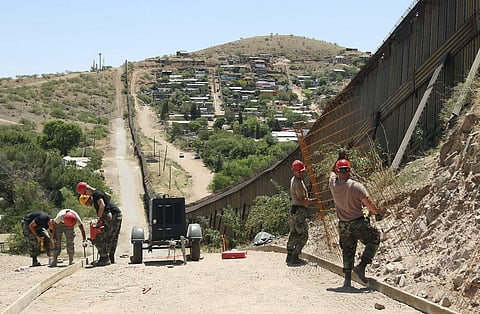 In this June 20, 2008 file photo, members of the 200th Red Horse Air National Guard Civil Engineering Squadron from Camp Perry in Ohio, including Tech Sgt. David Hughes, right, and Tech Sgt. William Bunker, second from right, work on building a road at th