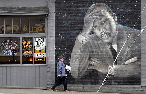 A man walks past a large mural of the Rev. Martin Luther King Jr. on the side of a diner, painted by artist James Crespinel in the 1990's and later restored, along Martin Luther King Jr. Way, Tuesday, April 3, 2018, in Seattle. | Associated Press