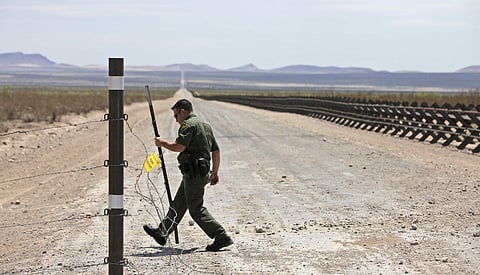 In this Aug. 6, 2009, file photo, U.S. Border Patrol Agent James Acosta opens a barbed wire fence leading to a road lined with vehicle barriers marking the U.S.-Mexico border near Hermanas, N.M. | Associated Press