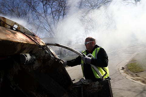In this March 23, 2018, photo, foreman Kenny Lane rides the back of a garbage truck as he works a residential route in Miamisburg, Ohio. | AP