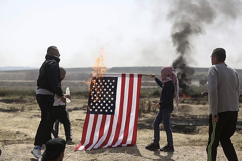 Palestinian protesters burn an American flag during a protest at the Gaza Strip's border with Israel. | AP