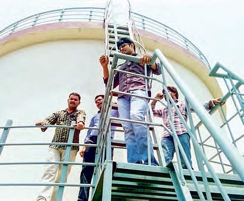 Contract assistant professors climb water tank opposing APPSC screening test, in Guntur on Friday | Express