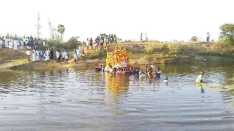 Dalit locals of Malaiyankuthagai of Ayakkaranpual 3rd Part Panchayat are taking the mortal into the river to reach the graveyard on Tuesday. (EPS)