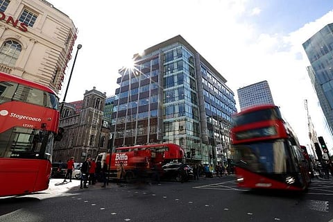 Traffic, including red London busses, passes the shared building which houses the offices of Cambridge Analytica in central London. | AFP