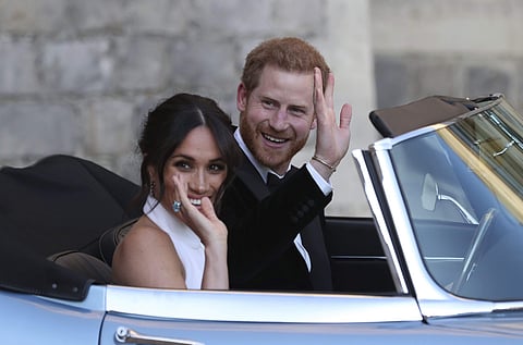 The newly married Duke and Duchess of Sussex, Meghan Markle and Prince Harry, leave Windsor Castle in a convertible car after their wedding in Windsor, England, to attend an evening reception at Frogmore House, hosted by the Prince of Wales on Saturday. (