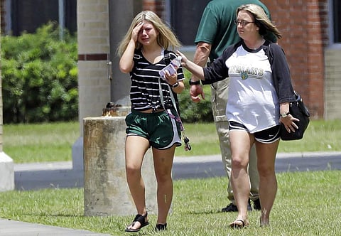 A student, left, reacts after retrieving her belongings inside Santa Fe High School in Santa Fe, Texas. | AP