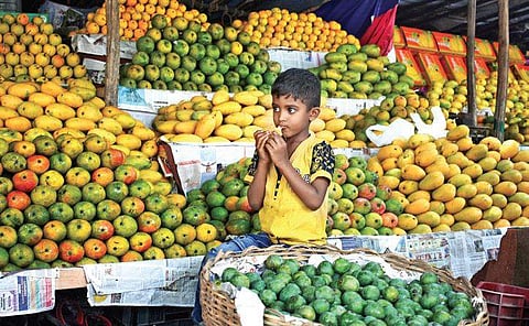 A child relishes a mango while her parents wait for customers at a stall on Jayamahal Main Road in Bengaluru on Sunday | Shriram BN
