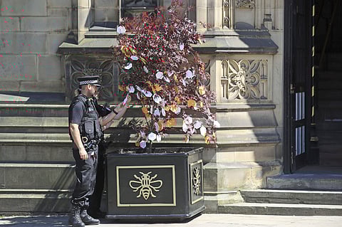 Police officers read messages left on a 'Tree of Hope' in Manchester, England ahead of the Manchester Arena National Service of Commemoration at Manchester Cathedral to mark one year since the attack on Manchester Arena, Tuesday May 22, 2018. (Peter Byrne