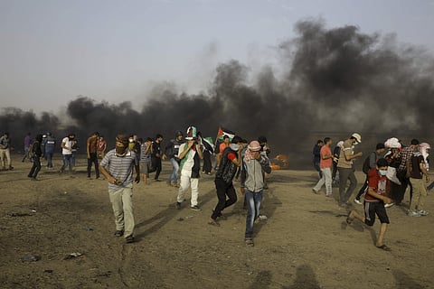 Palestinian protesters run for cover from teargas fired by Israeli troop near the fence of the Gaza Strip's border with Israel. | AP