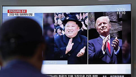 A man watches a TV screen showing file footage of Donald Trump and Kim Jong-un. | AP