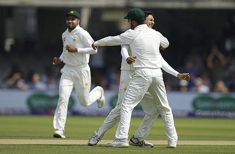 Pakistan's Mohammad Abbas, is hugged by a teammate as he celebrates after taking the wicket of England's Jos Butler lbw during the fourth day of play of the first test cricket match between England and Pakistan at Lord's cricket ground in London, Sunday,
