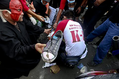 A masked demonstrator hands the blood stained shoe of wounded comrade to a friend as the other gets medical attention during a march against Nicaragua's President Daniel Ortega in Managua, Nicaragua, Wednesday, May, 30, 2018. | Associated Press