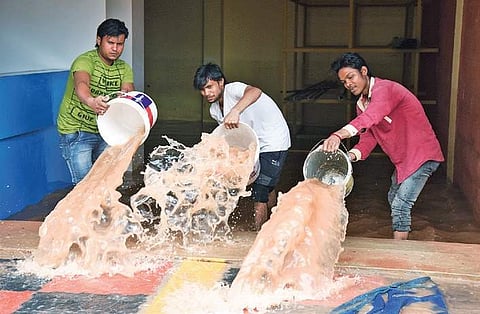 Employees of a furniture shop clearing rain water at Kottara Chowki on Wednesday | Rajesh Shetty Ballalbagh